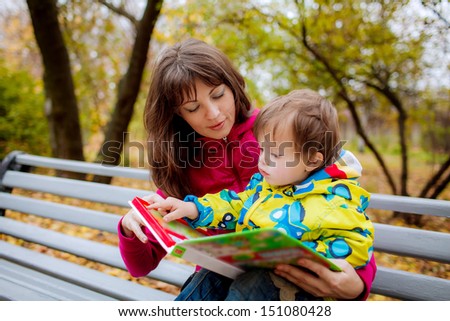 boy shows his finger in the book picture of his mother