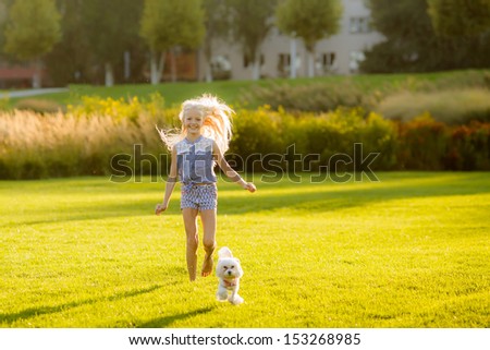 beautiful young blond woman with a dog breed lap dog running on the lawn in the park