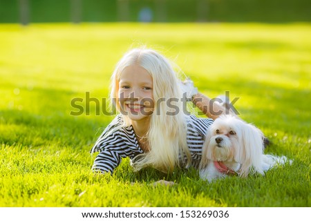 beautiful young blond woman with a dog breed lap dog in the park