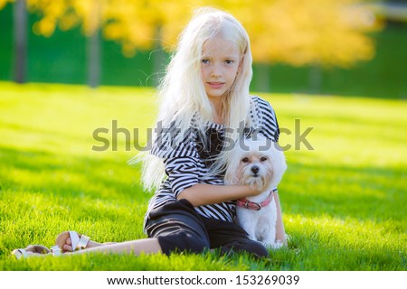 beautiful blonde girl playing with a dog lap dog in the park