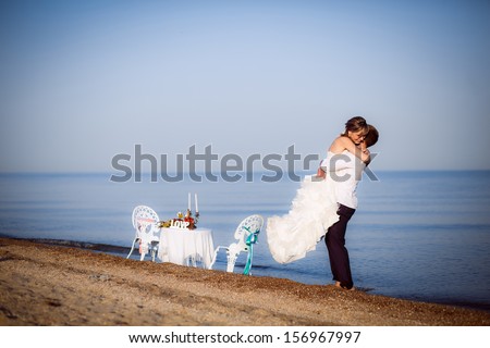 series. young couple walking along the beach. husband wears his wife in his arms