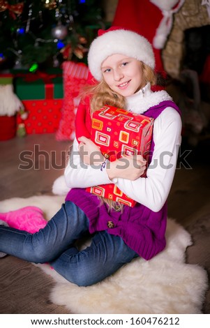 girl sitting by the fireplace and Christmas tree. Christmas hat. Christmas