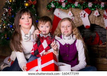 Happy family near the Christmas tree opening gifts. looking into the camera. smile. Christmas.