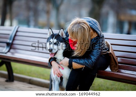 beautiful girl and dog Huskies walking around the city, the owner of the dog sitting on the bench