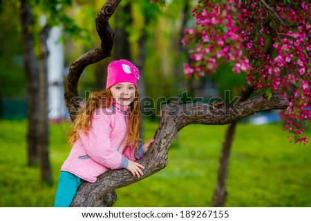 happy little girl in the park climbed on tree