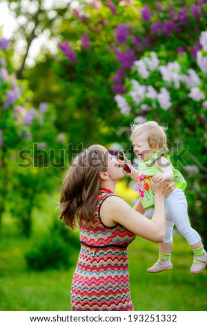 happy mother with baby garden of blooming lilacs. Mom throws baby. communication with the child mom. happiness. family