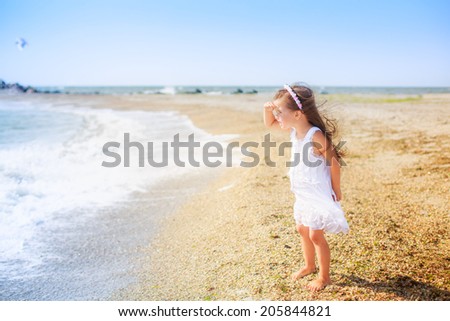 beautiful girl on the beach looking into the distance, wind