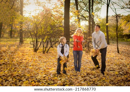 happy family in autumn park throws yellow leaves