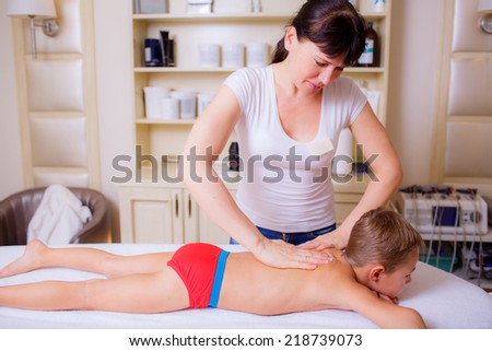 baby massage. masseur doing massage of the spine child 9-10 years
