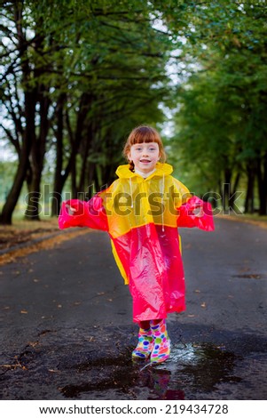 beautiful girl in rubber boots jumping in puddles