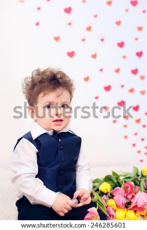 Beautiful curly-haired boy with a bouquet of tulips. International Women\'s Day, Mother\'s Day, March 8