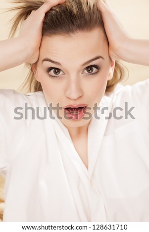 depressed young beautiful woman posing with her ??hands in her hair...