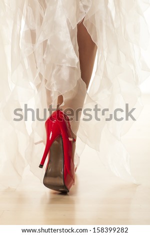 woman\'s leg in red high heels while walking