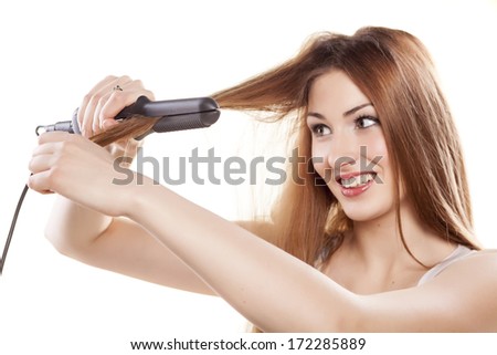 smiling redheaded girl straightens the hair using a hair straightener