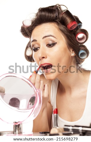 satisfied woman with curlers and bad makeup outlining the lips with a pencil