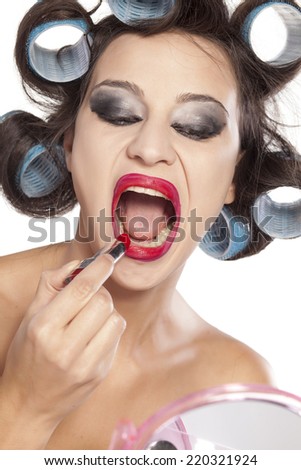 Funny woman with curlers and bad makeup applied lipstick