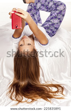 young woman with long hair lying on the bed and make a selfie