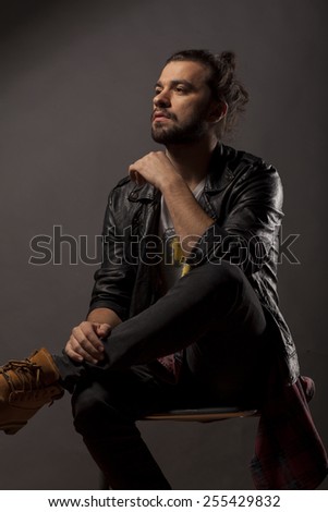 young man with beard and bun in black leather jacket