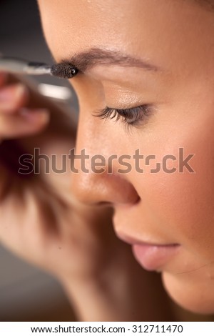 girl comb her eyebrows with a brow brush