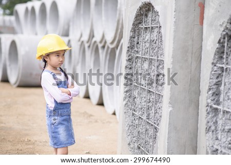 Kid civil engineer inspecting wire mesh on huge concrete pipe wall with worry mood