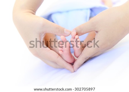 Baby feet with mom hand make a heart