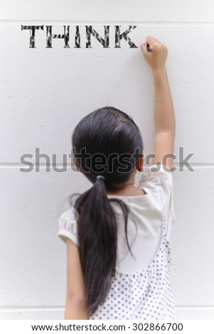 Kid writing think word on wall with her black pencil