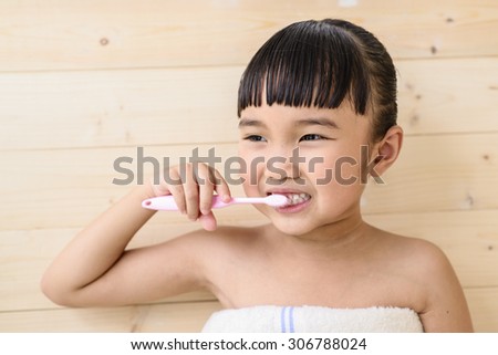 Little girl take a bath and brush teeth on wood wall background
