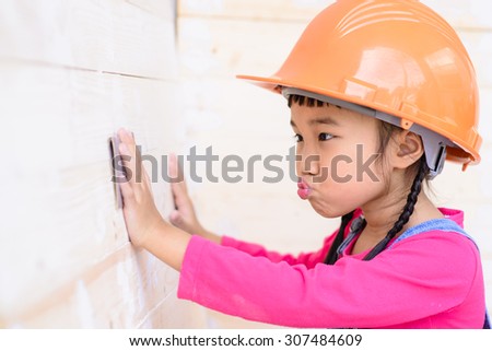 Little girl on carpenter work talent with sanding on wood