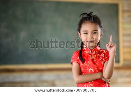 Little red girl on teacher pose with green blackboard background
