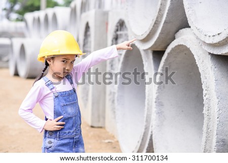 Kid civil engineer inspecting  huge concrete pipe and point to pipe