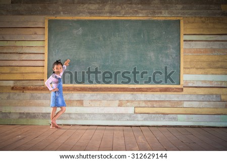 Little girl clear the green chalkboard in the old class room