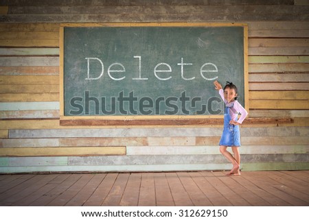 Little girl clear the green chalkboard in the old class room; Delete word on board