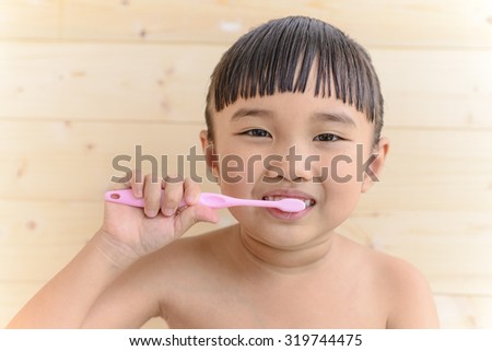 Little Asian girl take a bath and brush her teeth; Wood wall background