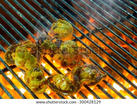 octopus Grilling sea food on the flaming grill. Summer barbecue concept seafood.