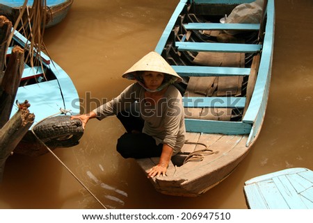 Ho Chi Minh City, Vietnam - Feb 19, 2009: Vietnamese woman floating on a boat on the yellow waters of the Mekong River