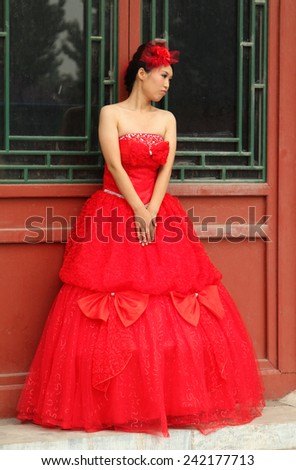 BEIJING, CHINA - JUL 4, 2011: Beautiful chinese woman in elegant red dress. Red is the main color of the traditional festive (including wedding) attire in China