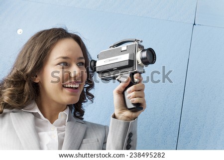 Young businesswoman in old fashioned style filming via antique camera