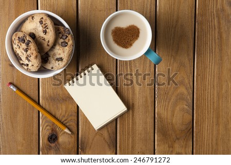 Cookie, cup of coffee and ring binder on table