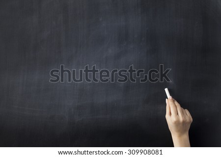 Close up of hand holding chalk on blank chalkboard