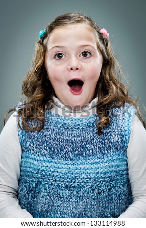 Little Girl with Surprise Expression Over a Grey Background