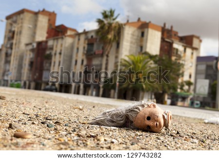 Broken doll head lying on the ground in a suburb on the outskirts of a mediterranean city