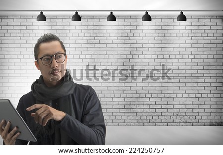 young man working on tablet and Blank frame on White Brick wall with Ceiling lamp