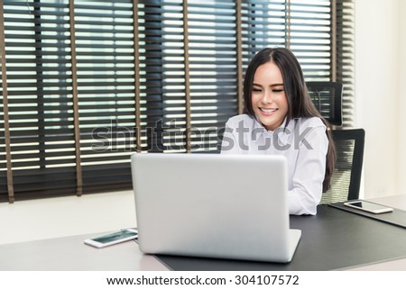 Beautiful business woman using a laptop computer at office, she is Happy and smiling face