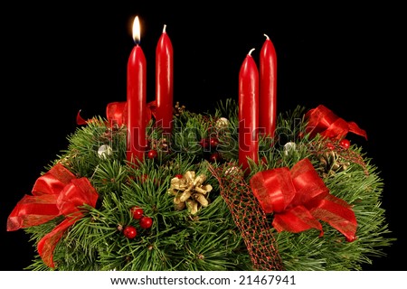 Advent wreath with red candles, one candle with flame. Isolated on black background.