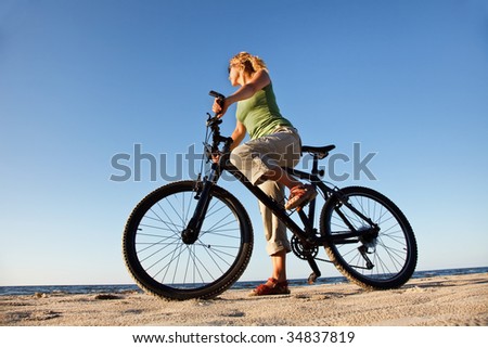 Young woman with bicycle at the sea low angle view
