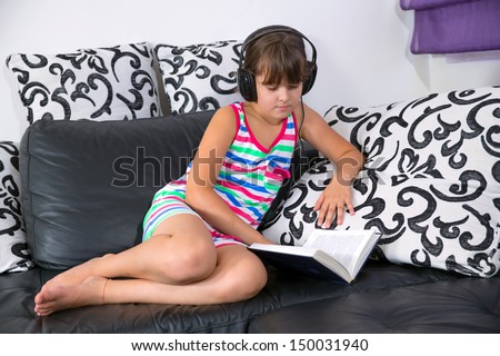 Pretty girl listening to music with headphones and reading a book
