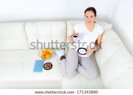 Beautiful pregnant woman drinking coffee on sofa at home