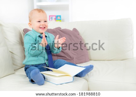 Little boy  reading the book, sitting on the sofa