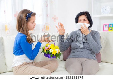 Cute girl giving a bunch of flowers to her grandmother.Grandmother has an allergy to flowers.