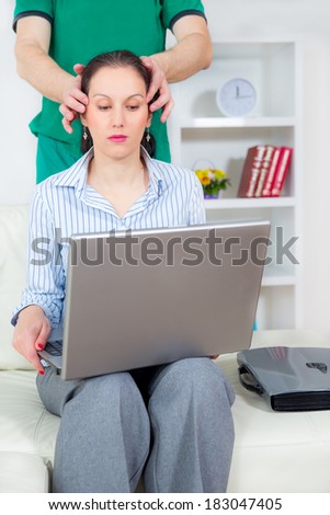 Business person on workplace with computer receiving neck massage from chiropractor